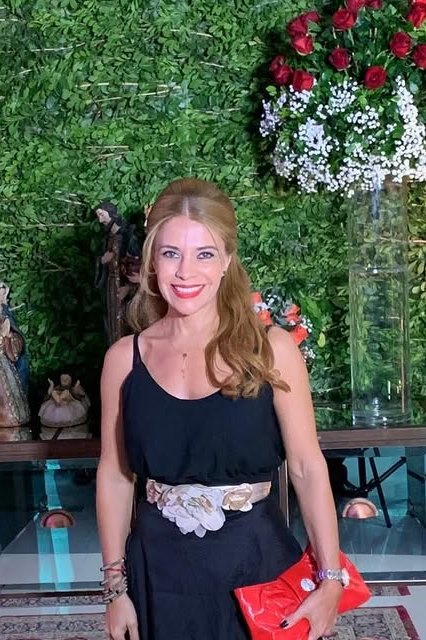 Cynthia Noguera con vestido negro y cartera roja en un evento